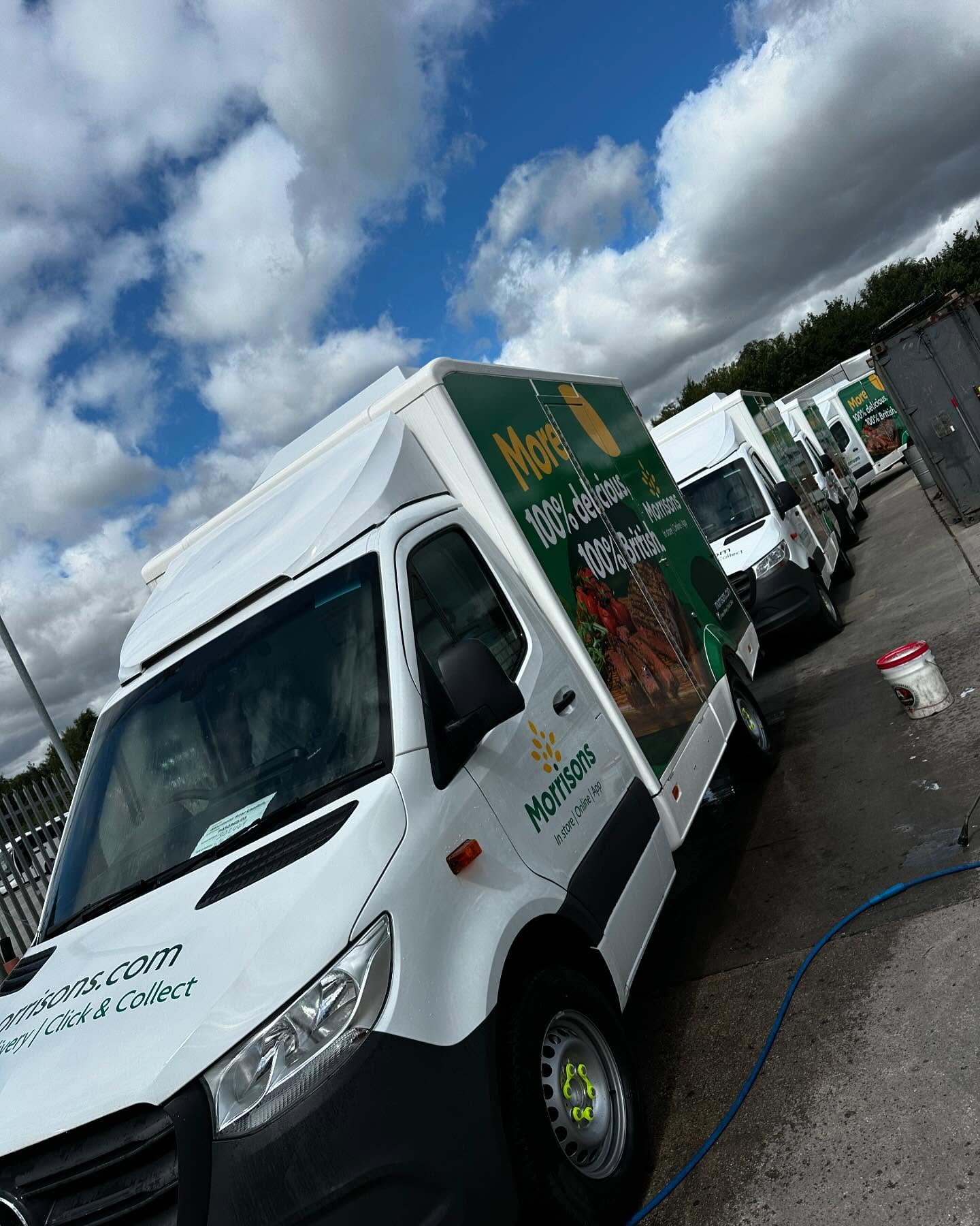 Line of branded commercial vans being washed on a commercial site